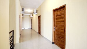 A long, narrow hallway with wooden doors and air conditioning units mounted on the wall. - OYO 1241 Eirini Family Homestay (Depok)