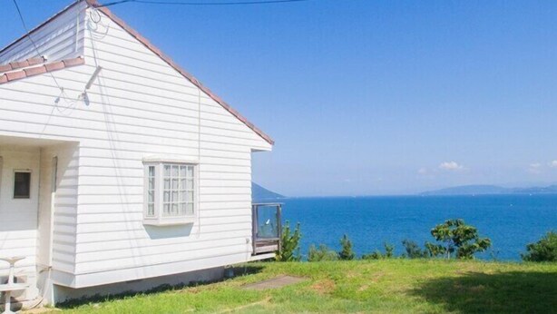 A white house with a small balcony overlooking a body of water. - Irou (Tonosho)