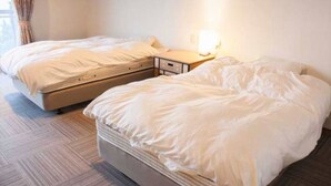 A hotel room with two single beds, a bedside table with a lamp, and a carpeted floor. - Irou (Tonosho)