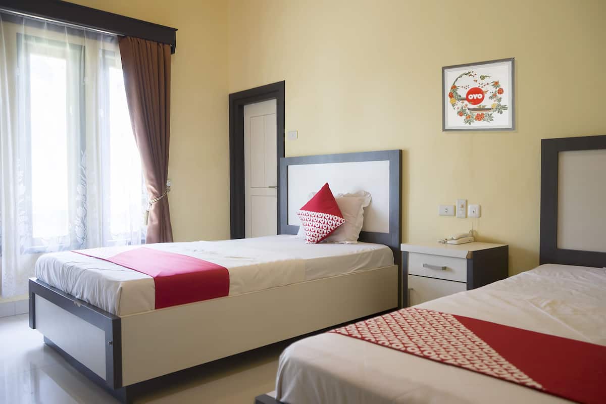 Habitación de hotel con dos camas, una mesita de noche, un cuadro en la pared y una ventana con cortinas.