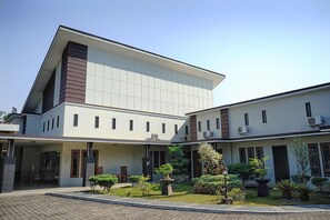 A modern building with a flat roof, multiple windows, and air conditioning units. - OYO 1283 Guest House Loemajan (Jambi)