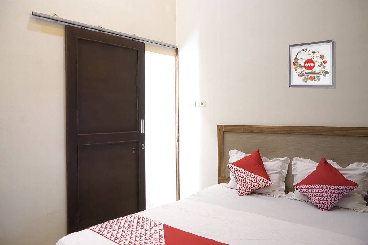 Una habitación de hotel con una cama, un armario y un cuadro en la pared.