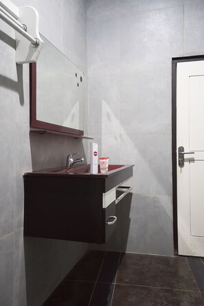 A bathroom with a dark vanity, a mirror, and a white door. - OYO 1283 Guest House Loemajan (Jambi)