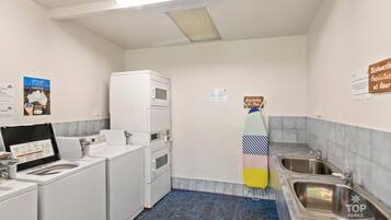 A compact hotel bathroom with a washing machine, a microwave, and a sink.
