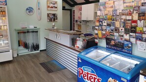 Un interior acogedor con una recepción, un reloj, una tabla de surf y una exhibición de productos locales.