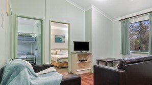 Una habitación moderna con sofá, televisor, literas y una ventana con cortinas.