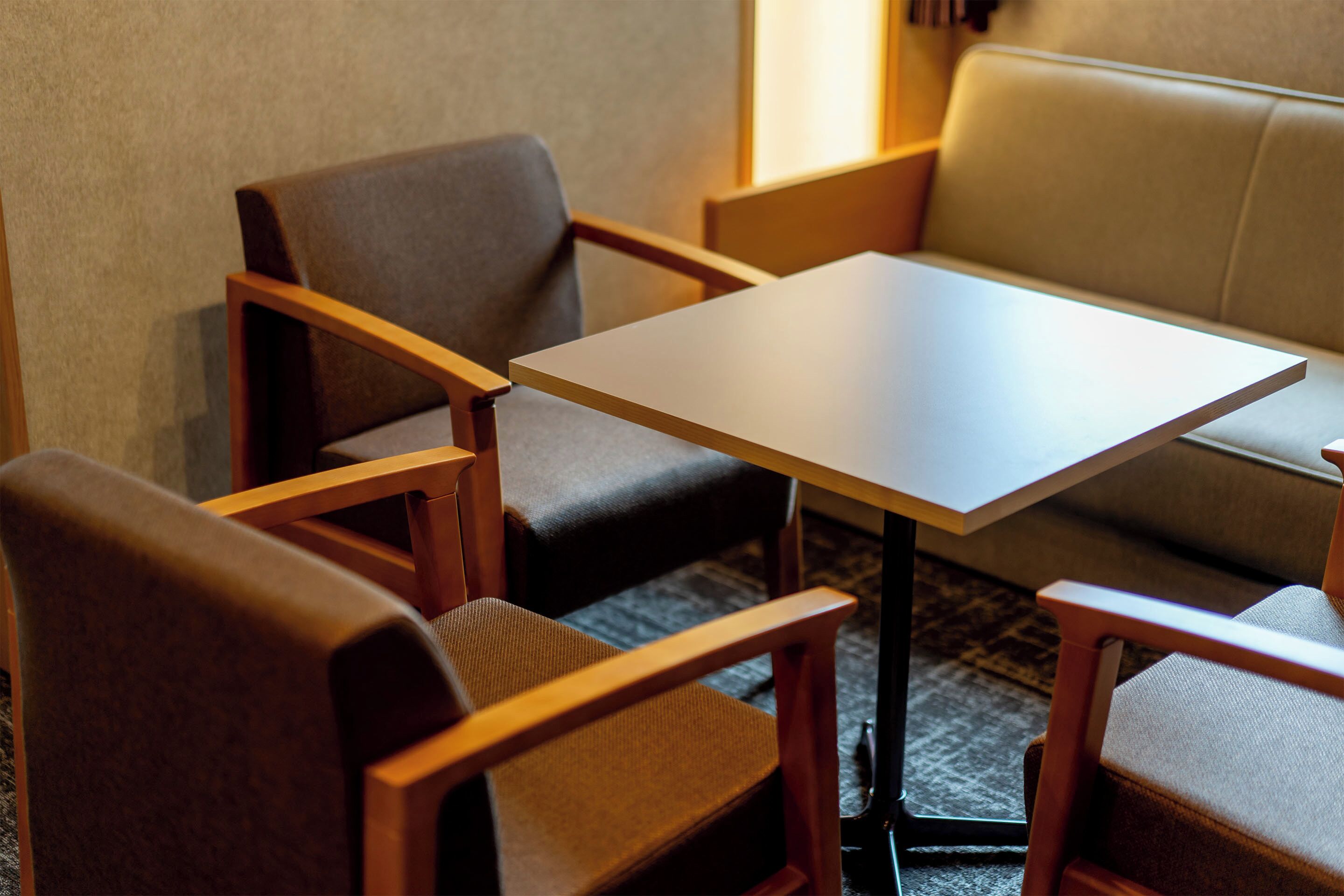 A small room with a table and four chairs, a sofa, and a carpeted floor.