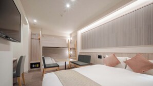Hotellihuone, jossa on sänky, työpöytä, tuoli, televisio ja vaatekaappi.