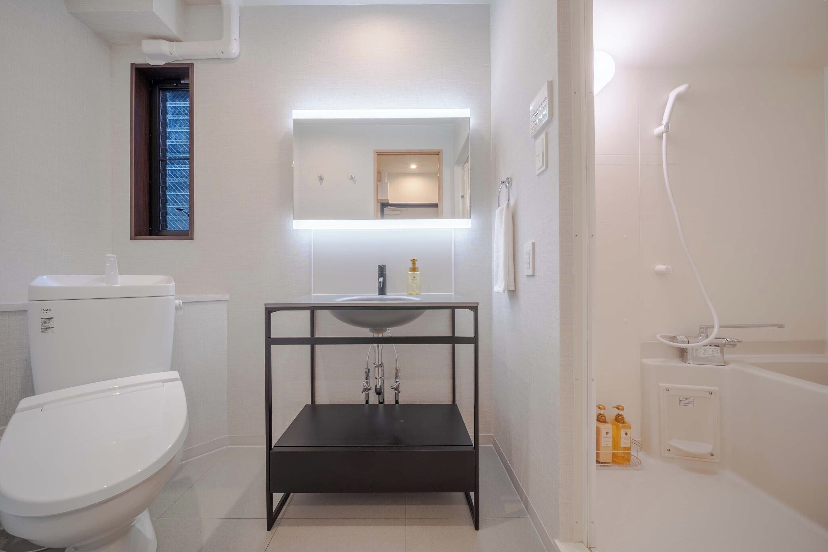 A bathroom with a toilet, a sink with a mirror above it, and a shower area.