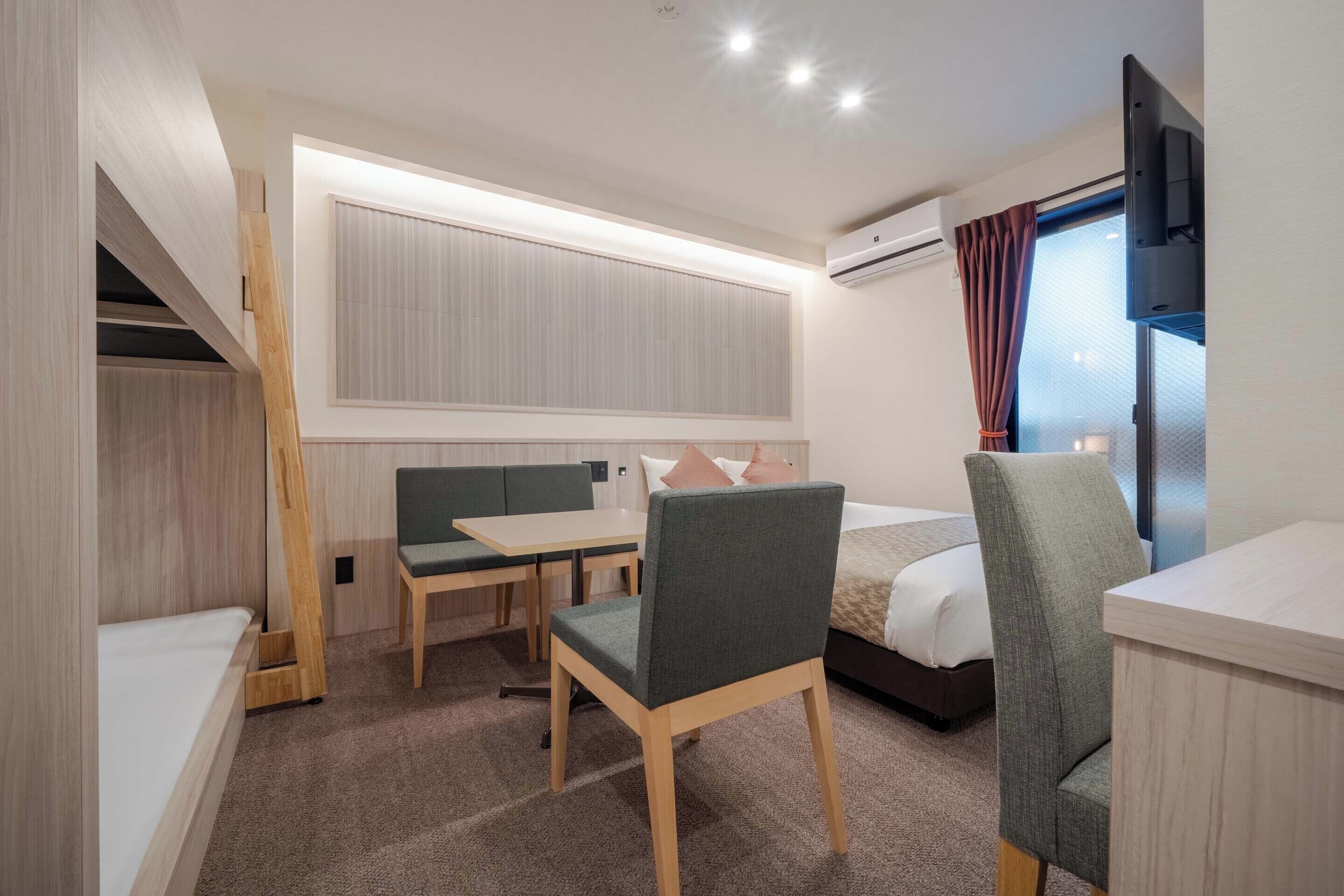 A hotel room with a bed, a desk, a chair, a TV, and a window with curtains.