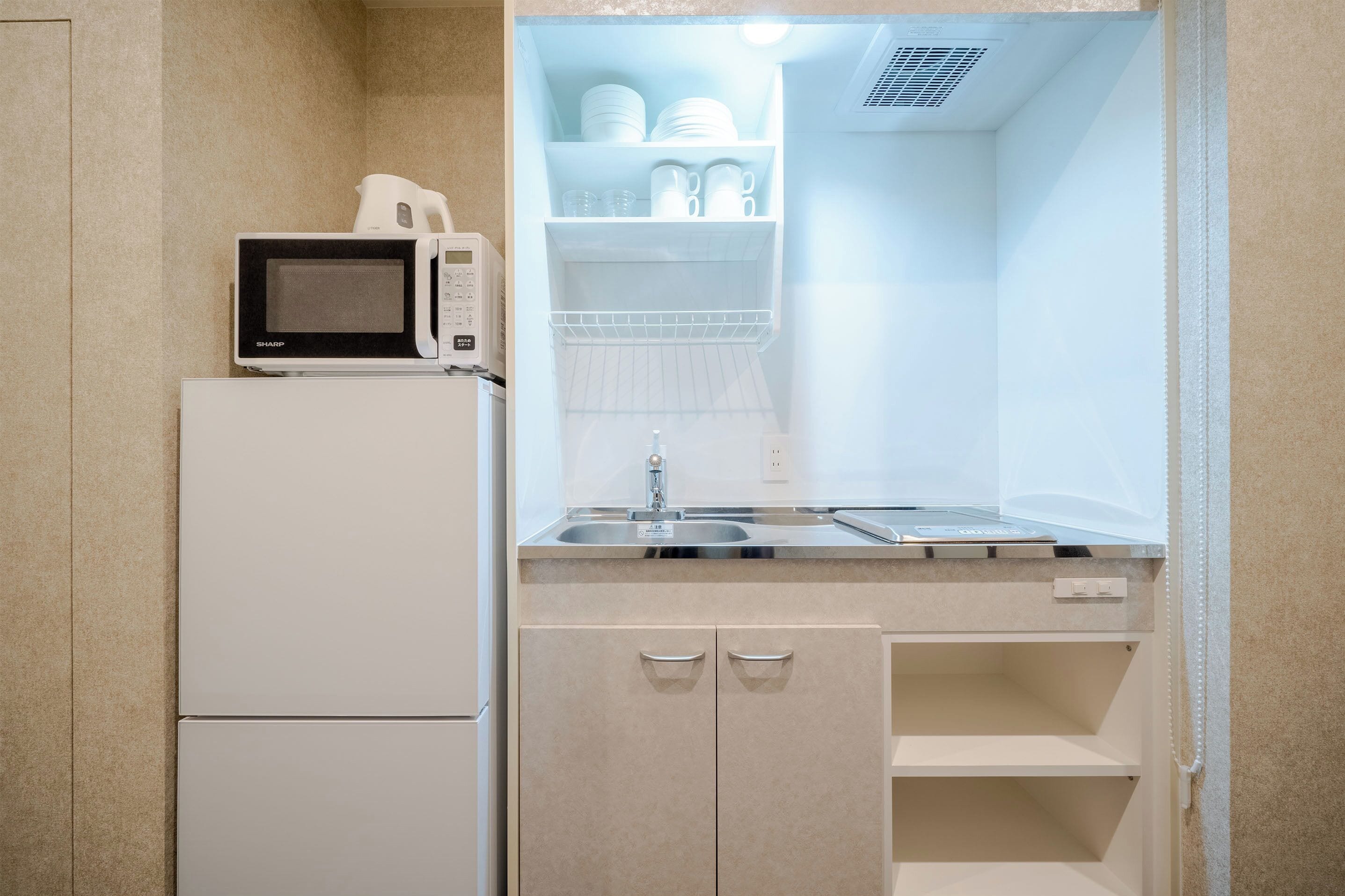 A compact kitchenette with a microwave, sink, and storage cabinets.