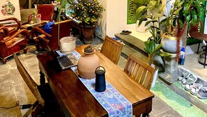 Un comedor con mobiliario de madera, plantas en macetas y un panel decorativo en la pared.