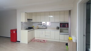 Una cocina con armarios blancos, un refrigerador rojo, un microondas y una estufa a gas.