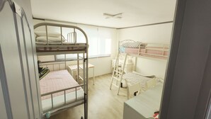 Habitación con literas, escritorio, silla, ventana y radiador.