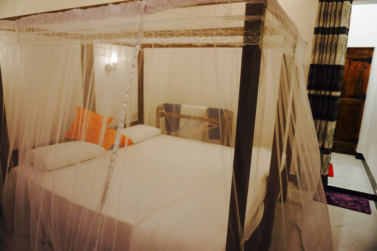 Ein Bett mit Baldachin, ein Nachttisch und ein Beistelltisch.