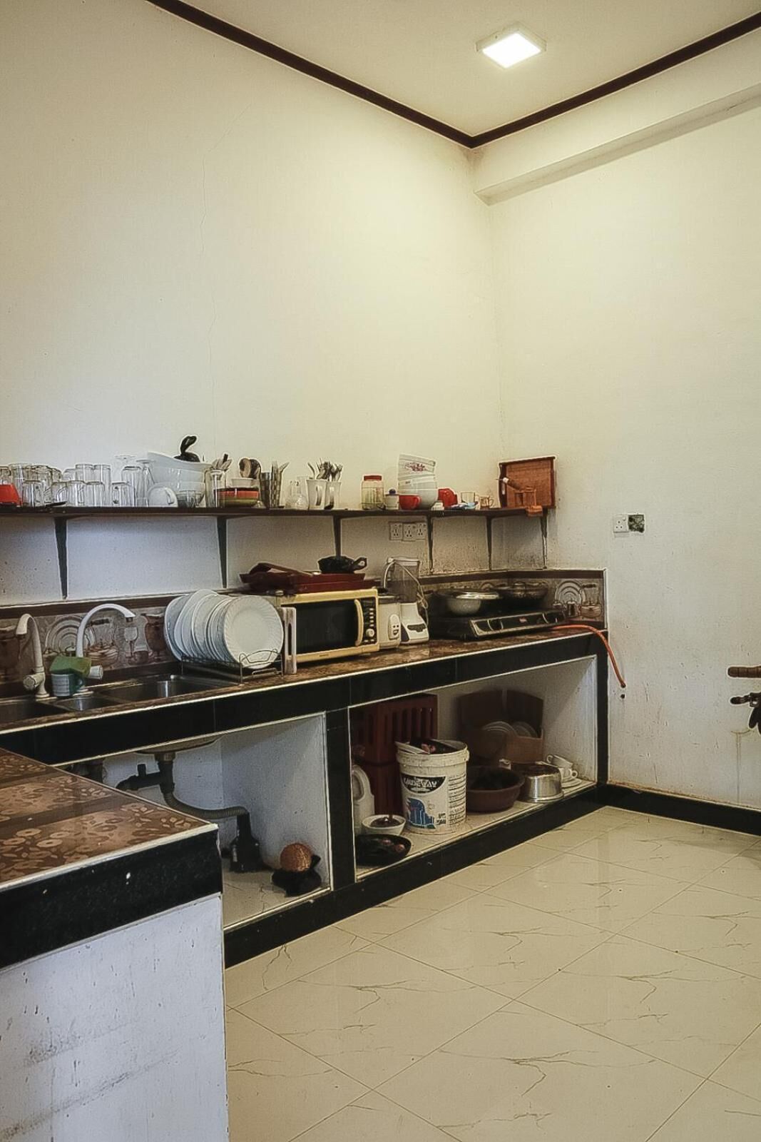 A small kitchen with basic appliances and a tiled floor.