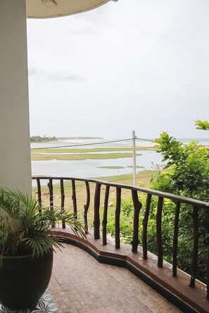 A balcony with a view of a water body and greenery. - Sunset view beach hotel (Arugam Bay)