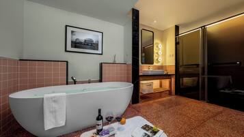 A modern bathroom with a freestanding bathtub, a vanity with a mirror and lights, and a framed picture on the wall.