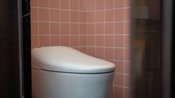 Eine weiße Toilette in einem Badezimmer mit rosa gefliesten Wänden.