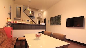 Um restaurante com um banco de madeira, uma mesa branca e uma TV na parede.