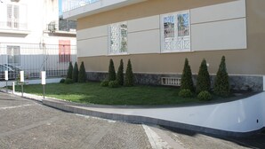 A modern building with a flat facade, large windows with metal grilles, and a well-maintained lawn with neatly trimmed bushes. - B&B Lapillus (Pompei)