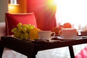 A tray with a white cup, a white saucer, a bunch of yellow grapes, and a yellow fruit on a wooden table. - B&B Lapillus (Pompei)