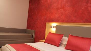 Habitación de hotel con una cama, una mesita de noche y una pared de acento roja.