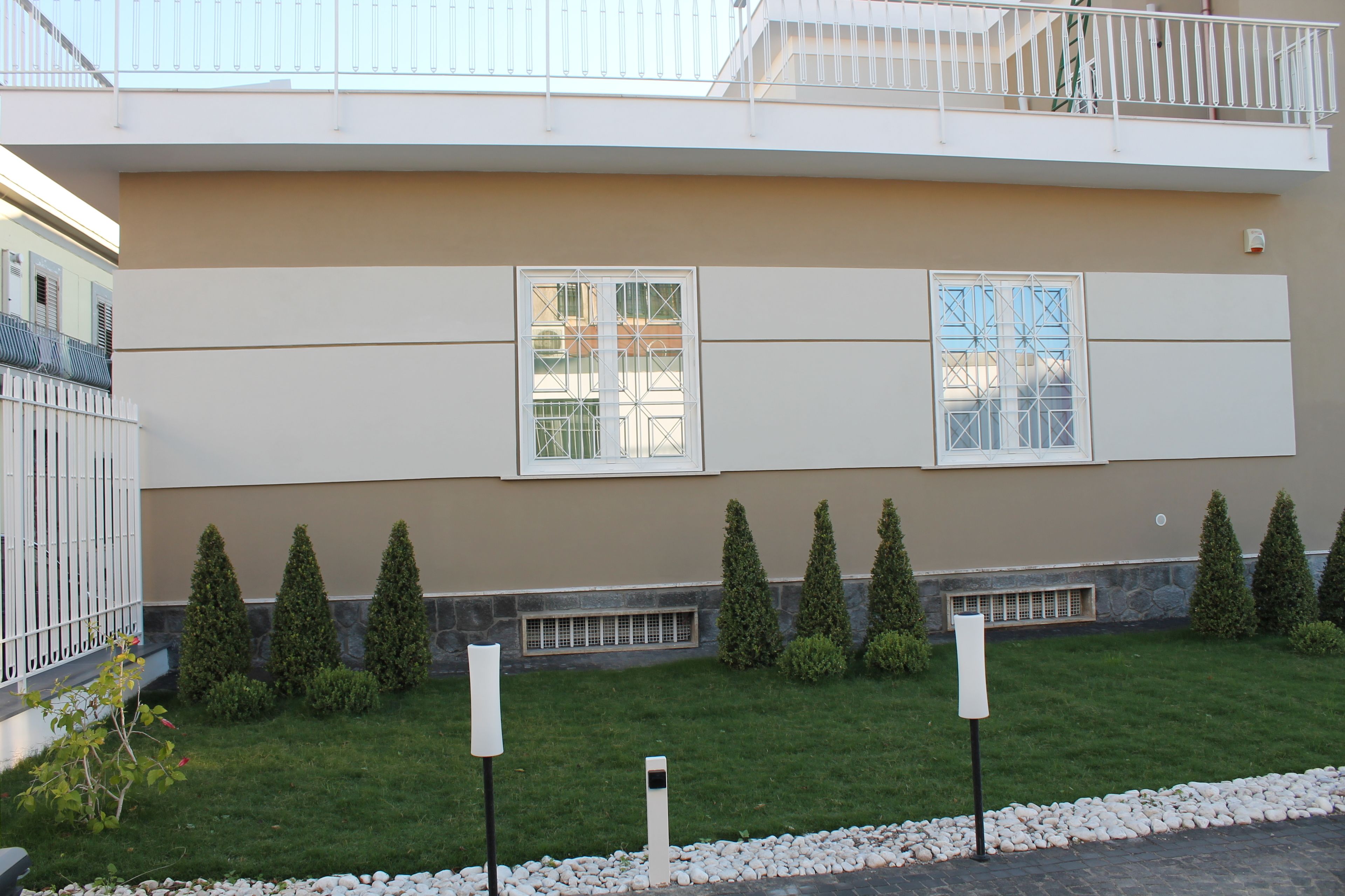 A modern building with two large windows, a well-maintained lawn, and a stone pathway.