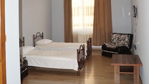 Ein Schlafzimmer mit einem Bett, einer hölzernen Bank, einem Sessel und einem Fenster mit Vorhängen.