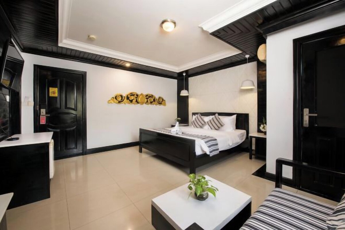 A modern bedroom with a black bed, white walls, and a decorative wall piece.