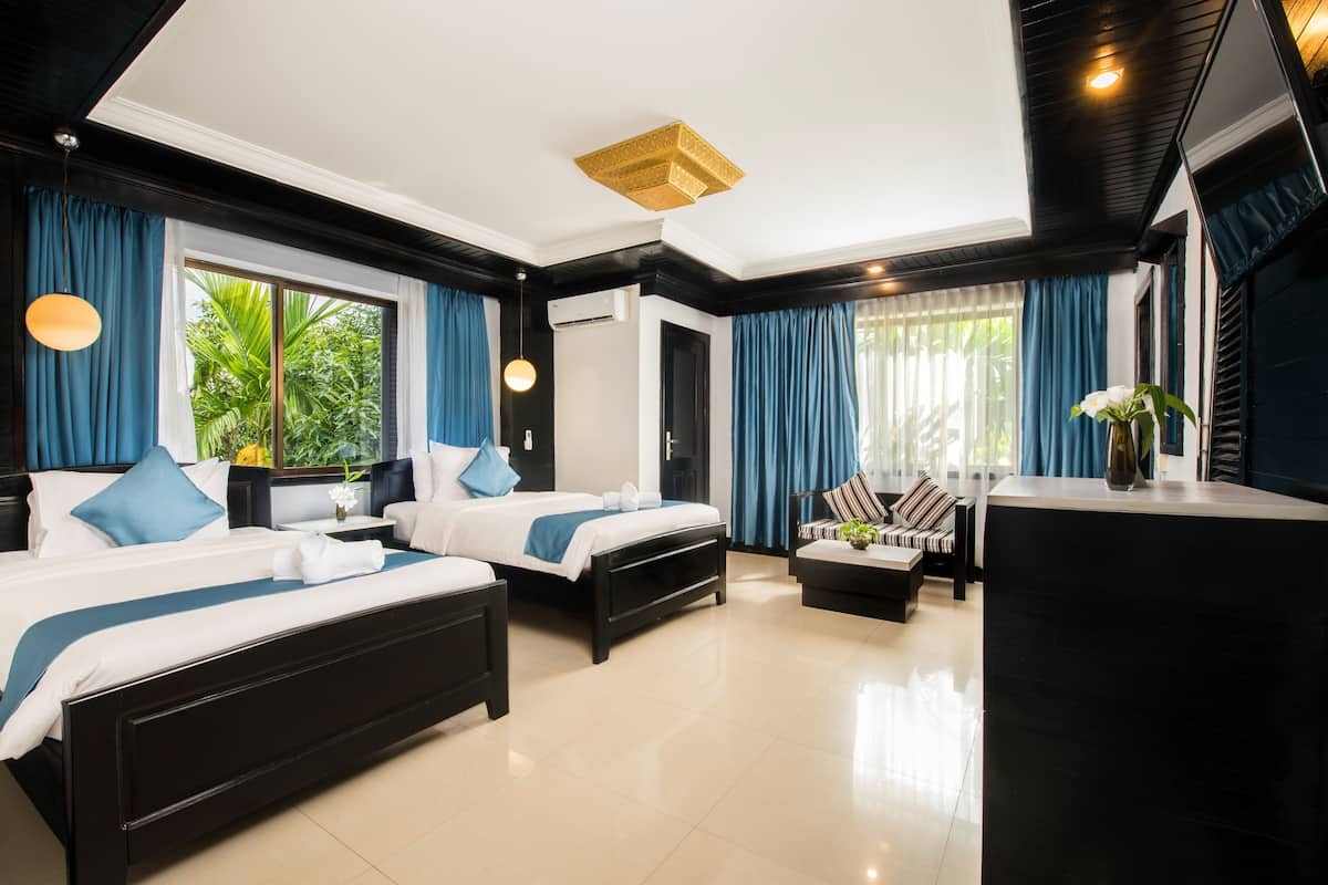 Quarto de hotel moderno com duas camas, um sofá e uma mesa de trabalho.