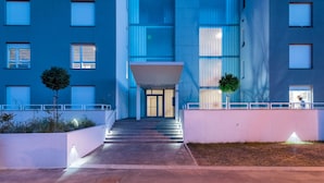 A modern building with a central entrance, multiple windows, and a well-lit pathway leading to the entrance. - StellaMare Apartments (Split)
