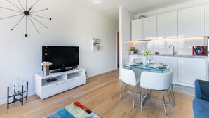 A modern living room with a flat-screen TV, a coffee table, and a dining area with chairs. - StellaMare Apartments (Split)