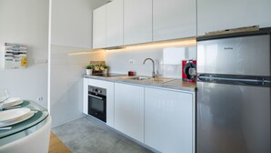 A modern kitchen with white cabinets, stainless steel appliances, and a glass dining table. - StellaMare Apartments (Split)