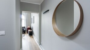 A hallway with a round mirror on the wall, a door leading to another room, and a chair in the distance. - Elite Apartments Loft Center (Gdansk)