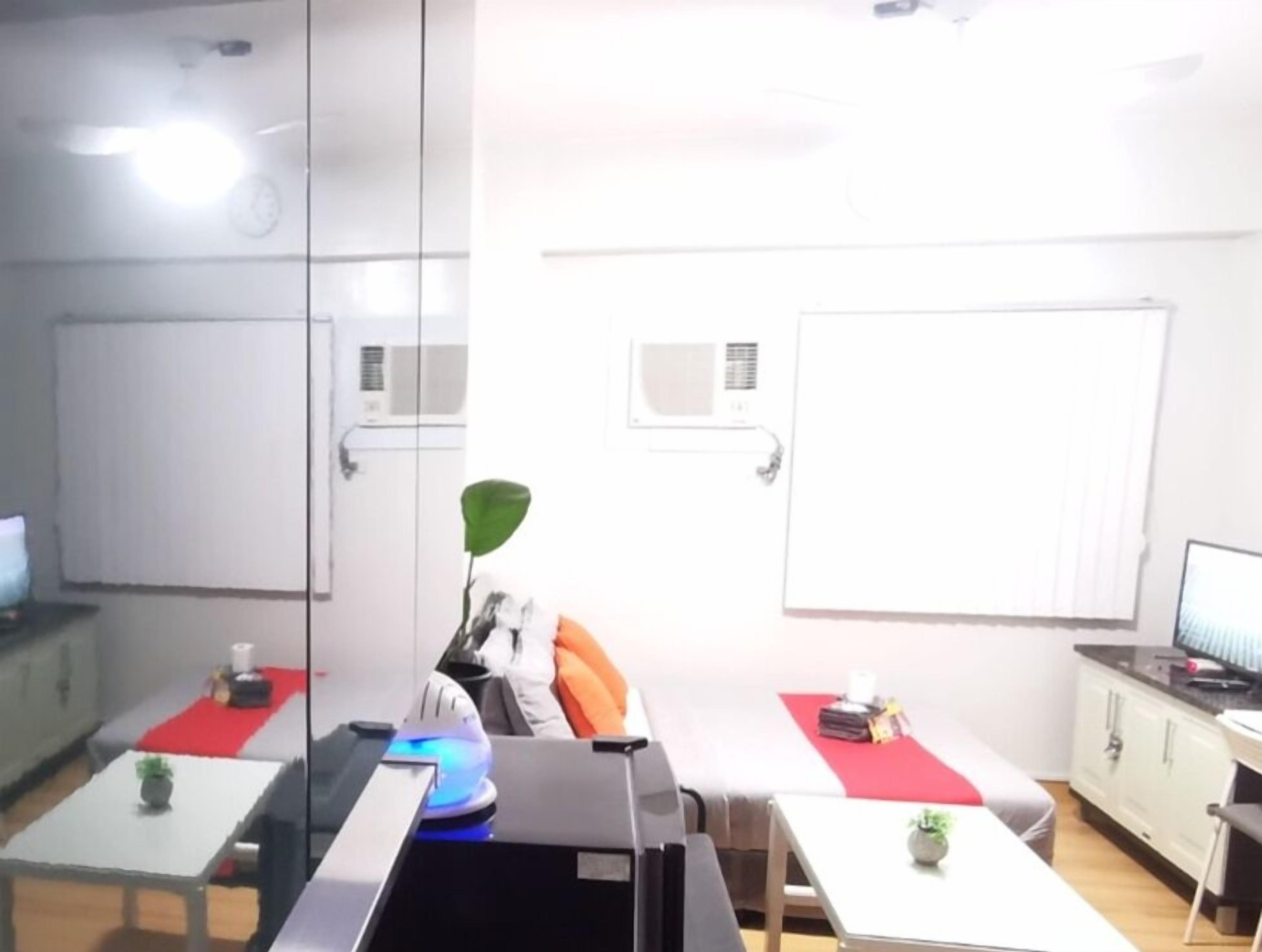 A modern office with glass partitions, white walls, and a red carpet. There are desks with computers and a plant.