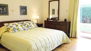 A bedroom with a bed, a dresser, a mirror, and a window with curtains. - Glyfada Spacious Apartment Garden (Glyfada)