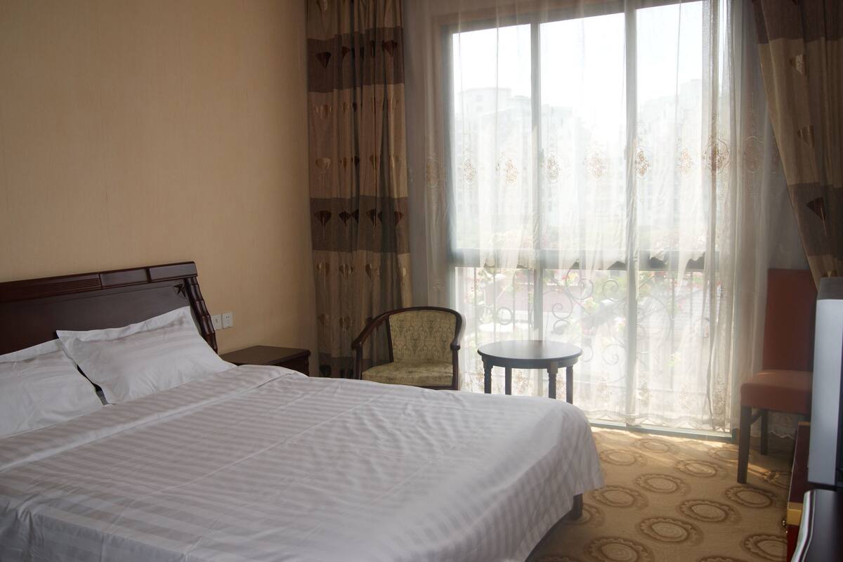 A hotel room with a bed, a chair, a small table, and a TV.