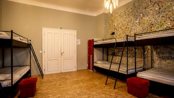 A room with bunk beds, a wooden floor, a white door, and a wall with abstract art.