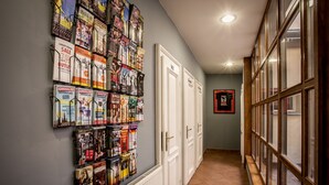 A hallway with a wall of magazines and a row of white doors. - Ahoy! Hostel (Prague)