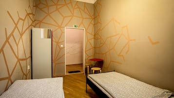 A room with two beds, a small table, and a refrigerator.