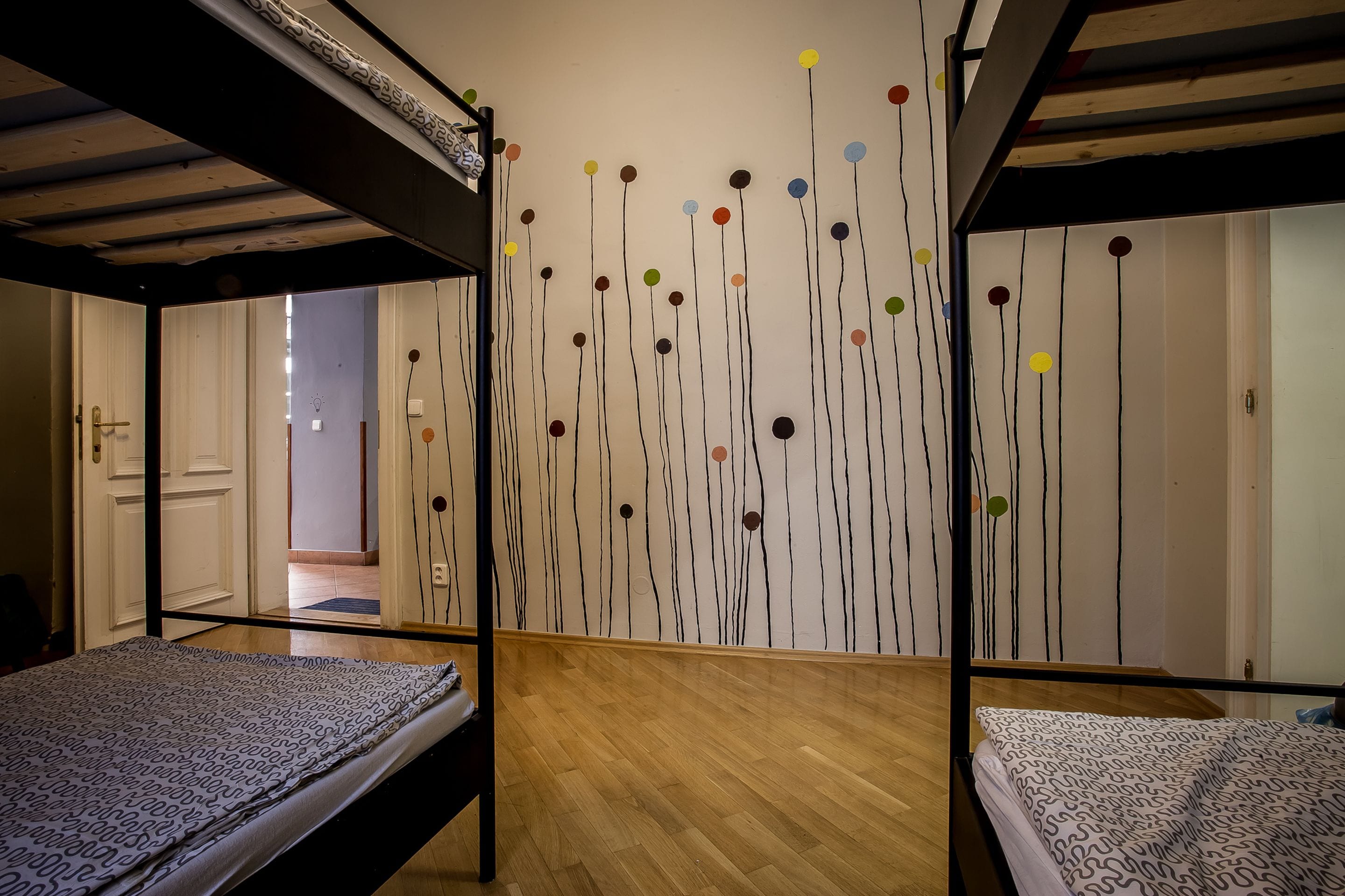 A room with bunk beds, wooden flooring, and a wall with vertical lines and colorful dots.