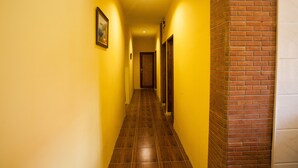 A narrow hallway with yellow walls and a wooden floor.