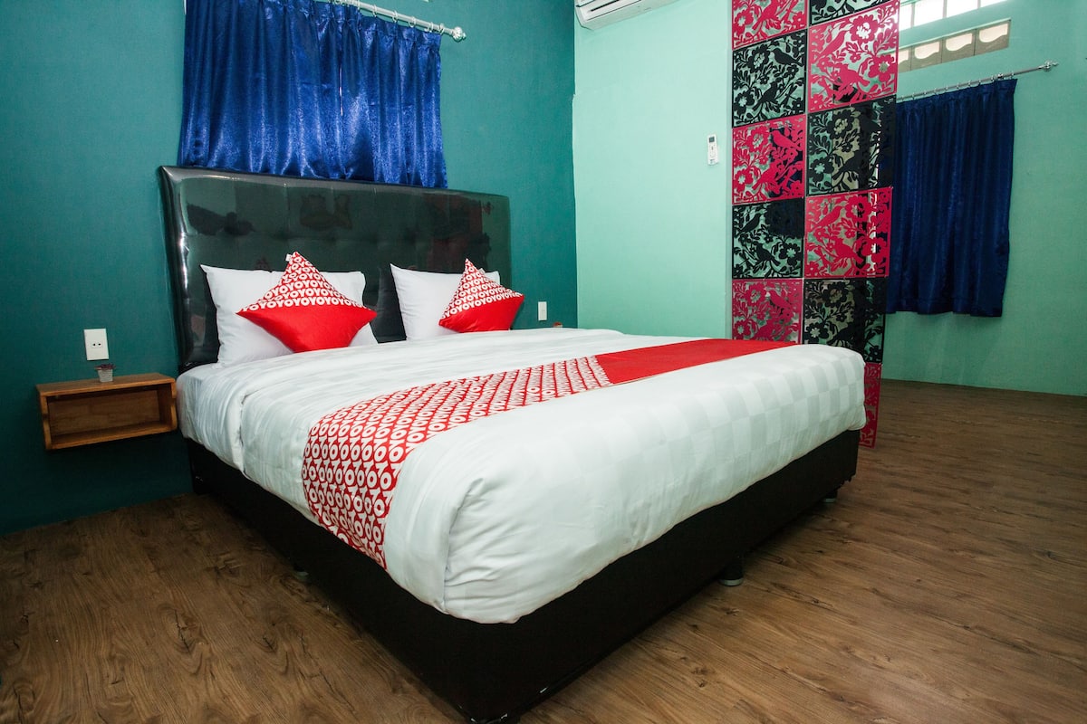 A neatly made bed with a patterned bedspread, a headboard, and two pillows.