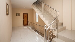 A modern interior with a staircase, a wooden door, and a framed picture on the wall.