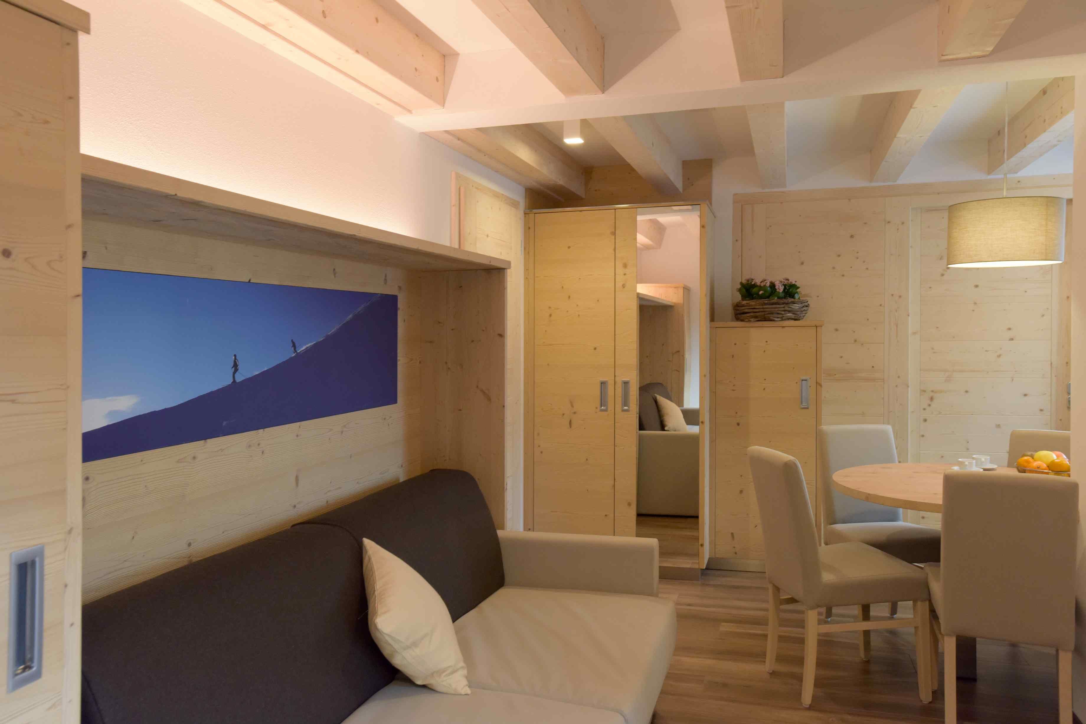 Una camera moderna con soffitto in legno, un divano, un tavolo da pranzo con sedie e un quadro appeso al muro.