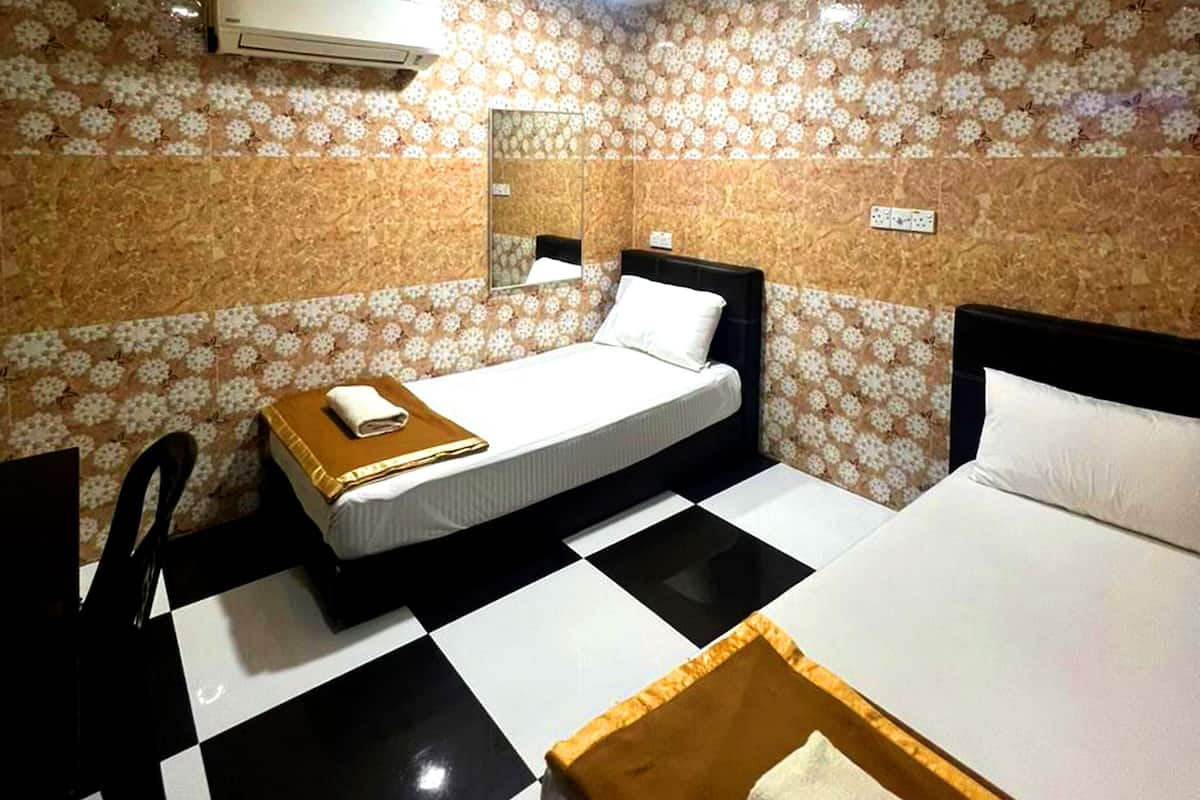Habitación de hotel con dos camas, piso de cuadros, papel tapiz floral y un espejo.