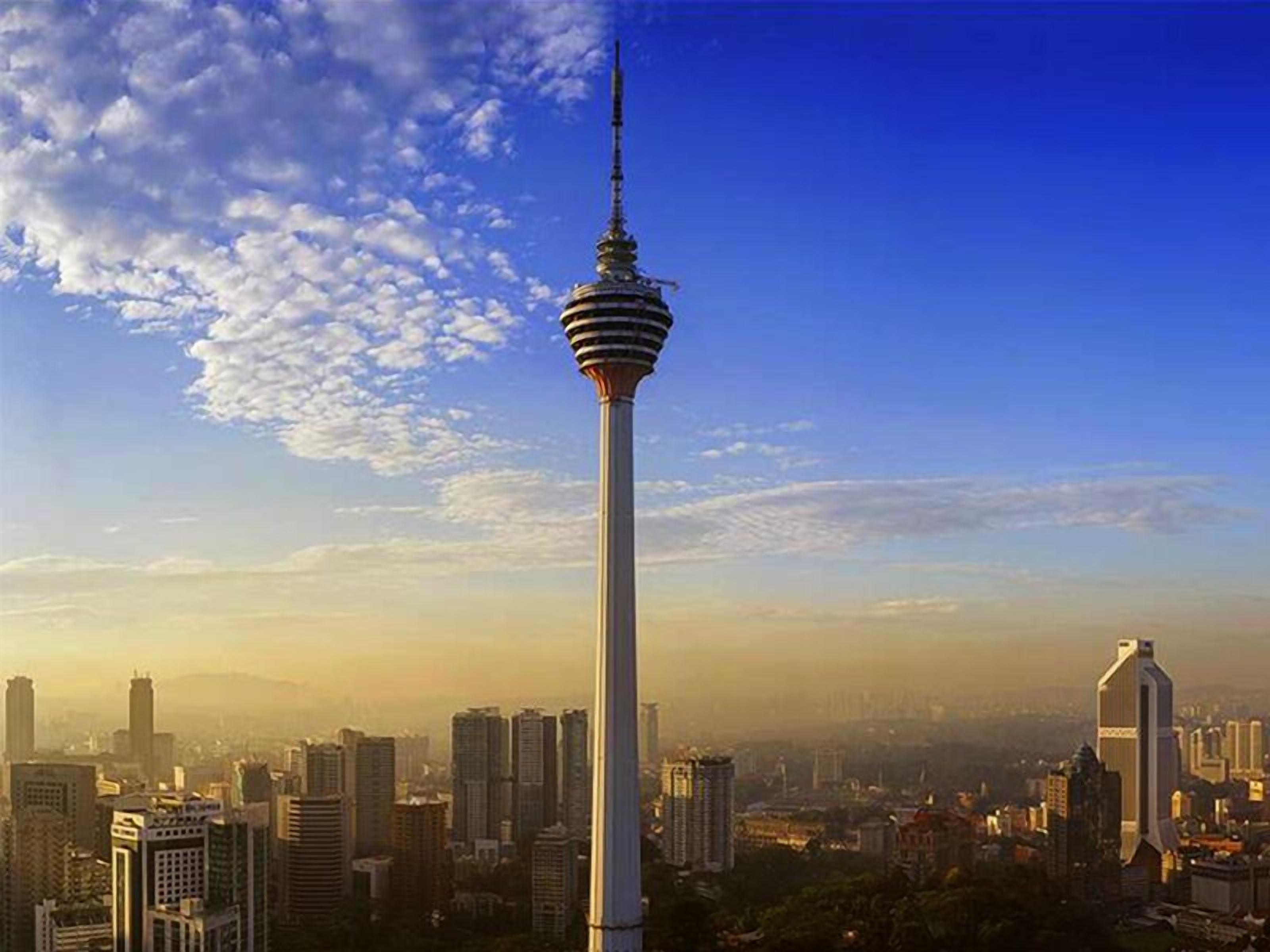 A tall tower with a spire, surrounded by a cityscape with various buildings.