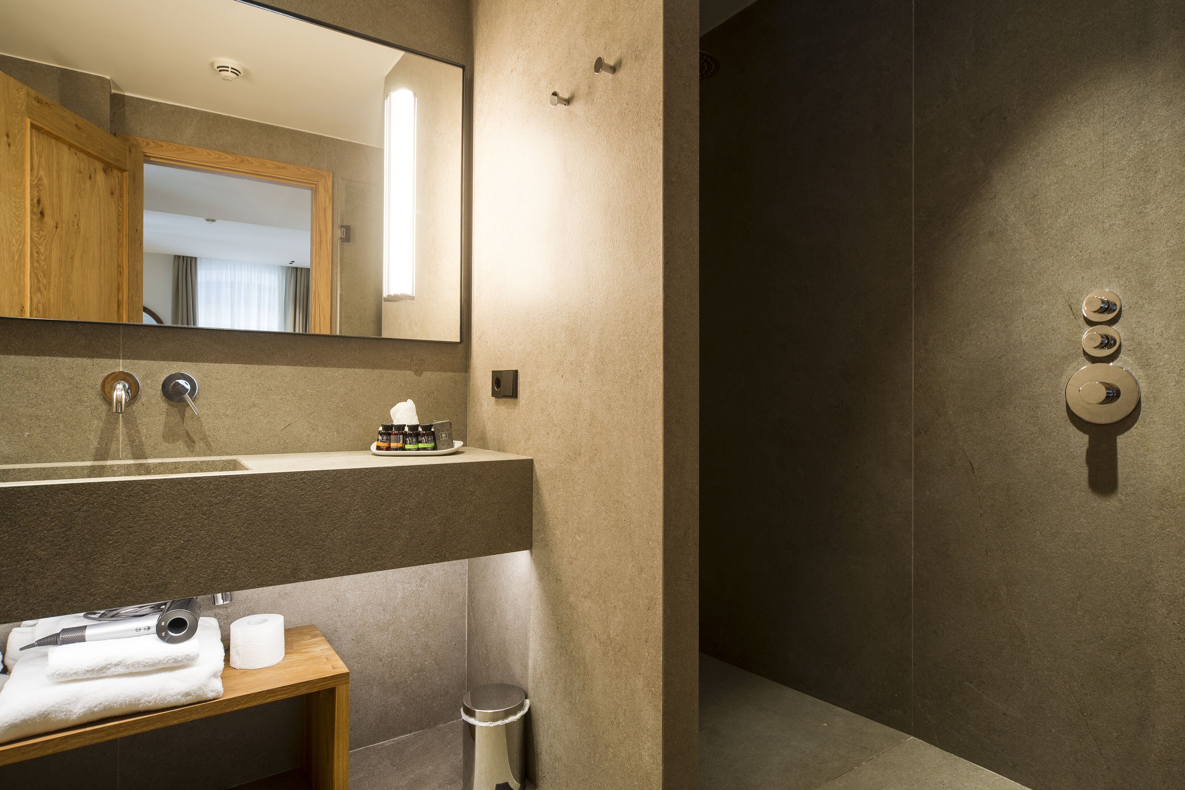 Une salle de bain moderne avec un grand miroir, un lavabo avec une serviette et des toilettes.