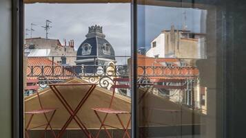 Un balcón con mesa y sillas, con vistas a un paisaje urbano de arquitectura distintiva.